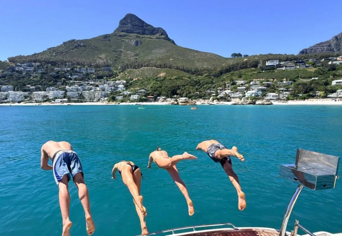 Four guests diving off Wu Wei at Clifton with Lion's Head behind