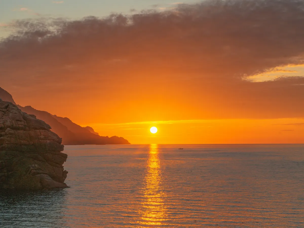 The sun setting into the Atlantic off Camps Bay, Twelve Apostles in silhouette